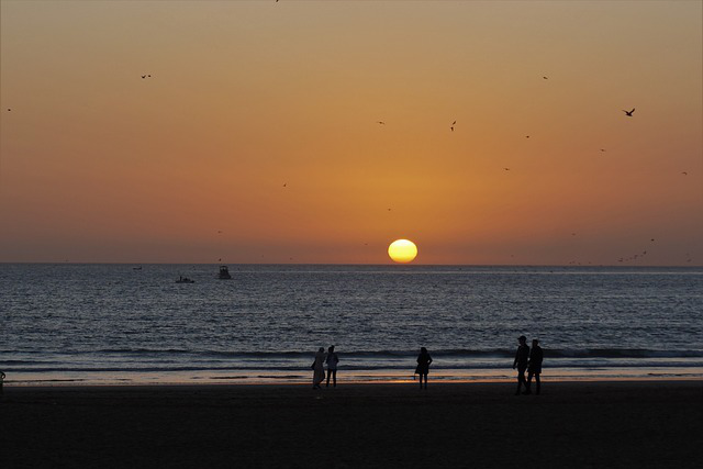 Coucher de soleil sur la plage d'Agadir, avec des teintes orangées illuminant l'horizon et des vagues douces de l'océan Atlantique